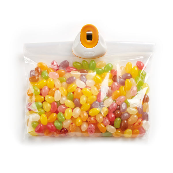 A clear resealable plastic bag of assorted colorful jelly beans is sealed with a Zyliss Clip-All Bag Clip (Mixed Sizes) in orange and white—a kitchen essential for preventing food spillage.