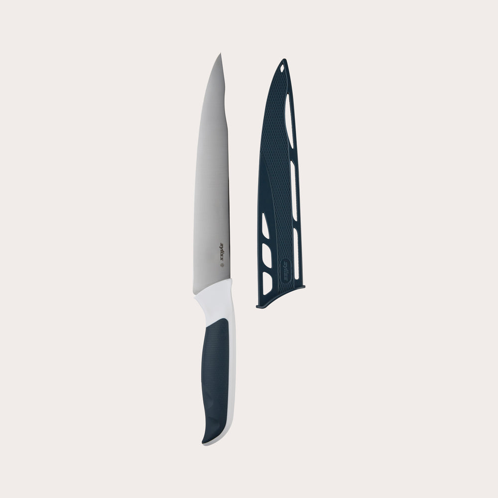 The Zyliss Comfort Carving Knife 18.5cm (7¼) with a black and white handle and comfortable grip is pictured beside its black protective sheath on a plain light background.