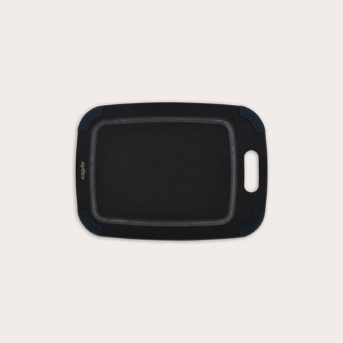 The Zyliss Wood Fibre Cutting Board is rectangular with rounded edges, a built-in handle, and dark blue corner grips. Made from recycled wood fibres, it is shown on a plain light background. #Small