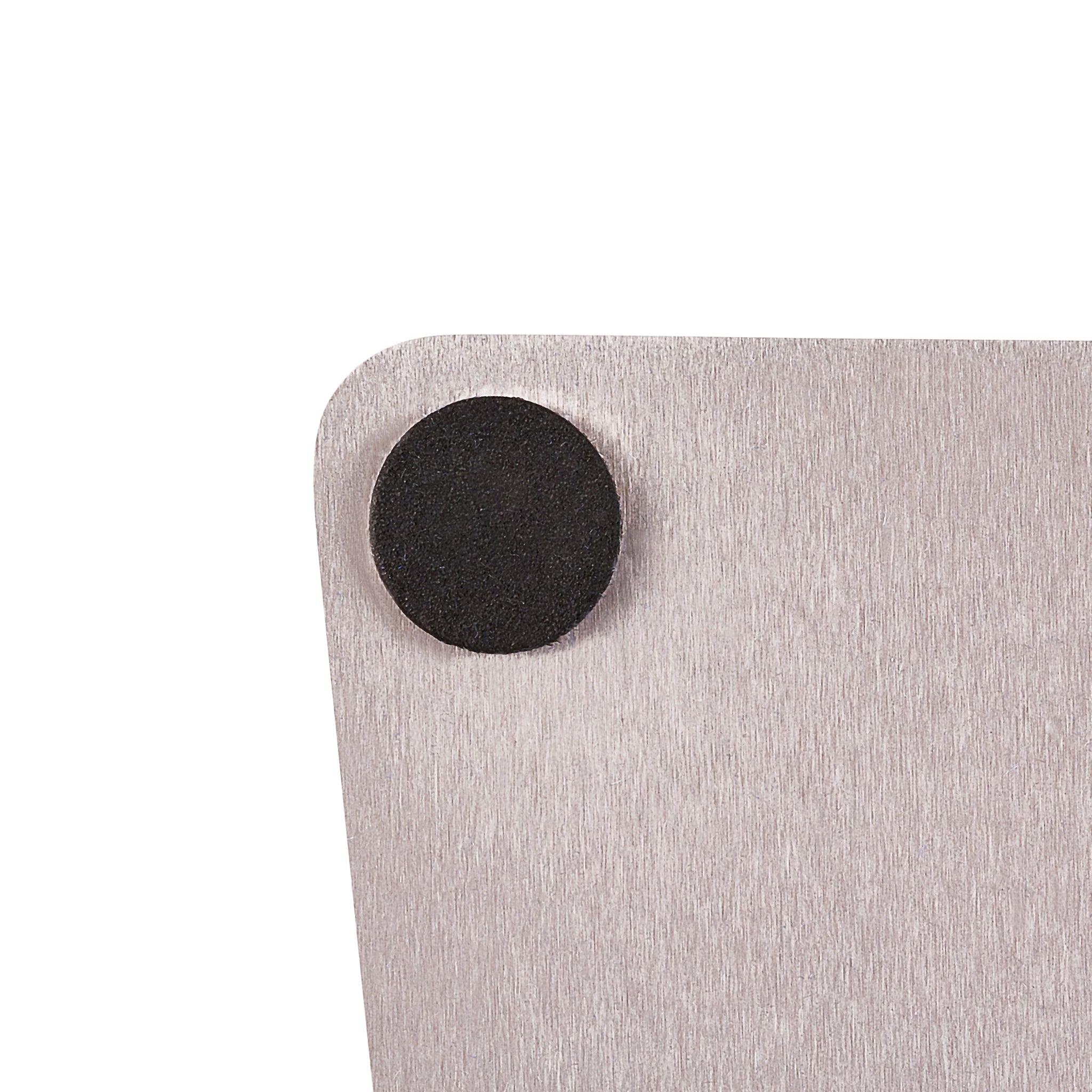 Close-up of a rectangular metallic surface with a brushed texture, featuring a round black rubber pad attached near the top left corner.