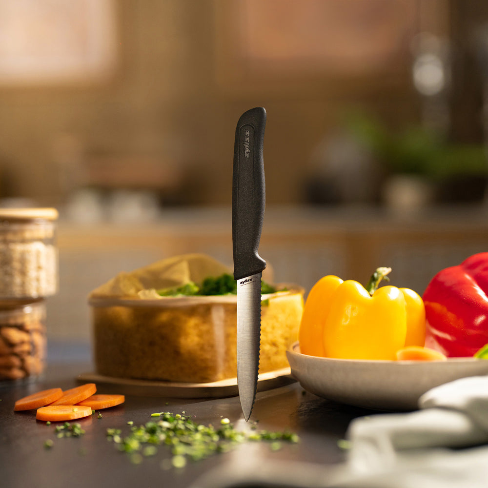 A Zyliss Paring Knife Serrated 10cm/4" with an ergonomic black handle stands vertically on a plain light background. A circular label in the top right corner displays "4 for 3 mix & match" in bold text.