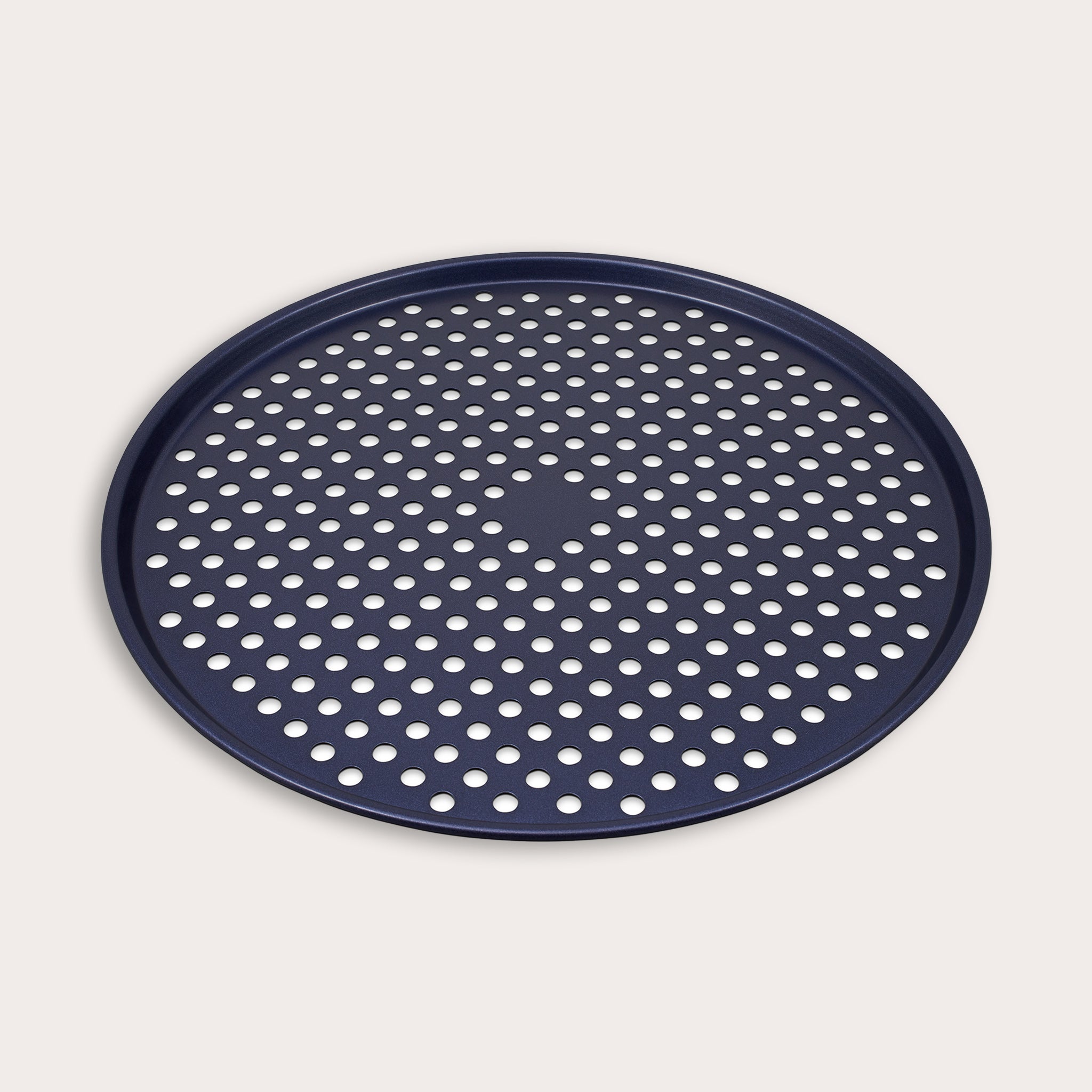 The Zyliss Durable Non-Stick Pizza Tray is a round, dark blue metal tray with raised edges and a perforated base featuring evenly spaced holes for optimal baking, shown against a plain light background.