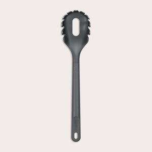 The Zyliss Spaghetti Server is a black, heat-resistant utensil with a long handle and slotted, rounded head featuring prongs for ideal portion control, shown isolated on a light background.