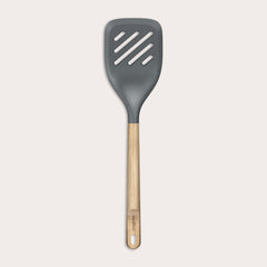 The Zyliss Oak Wood Slotted Turner is a kitchen essential with a wide, dark gray head and light oak wood handle, shown on a plain white background.