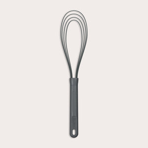 The Zyliss Flat Whisk Silicone features a black, heat-resistant silicone design with a long handle and looped wires, displayed on a plain light background.