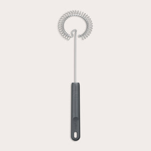 The Zyliss Gravy Whisk features a metal spiral and a dark plastic handle with a hanging hole. It is heat-resistant and shown against a plain light background.