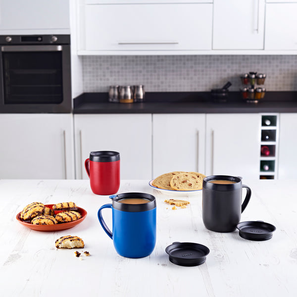 Ideal for coffee lovers, the Zyliss Hot Mug Cafetière Mug features double-wall insulation to keep drinks hot—perfect for sipping fresh coffee in a modern white kitchen alongside bread and cookies. #red