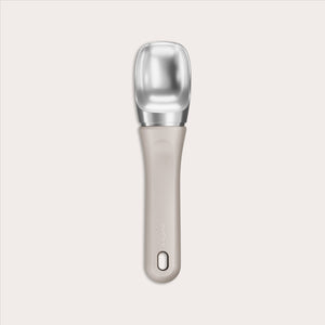 #naturalbeige The Zyliss Ice Cream Scoop features a wide, flat silver scoop and an eco-friendly beige handle made from sustainable wheat straw, with a small hole near the end, shown centered on a plain light background.