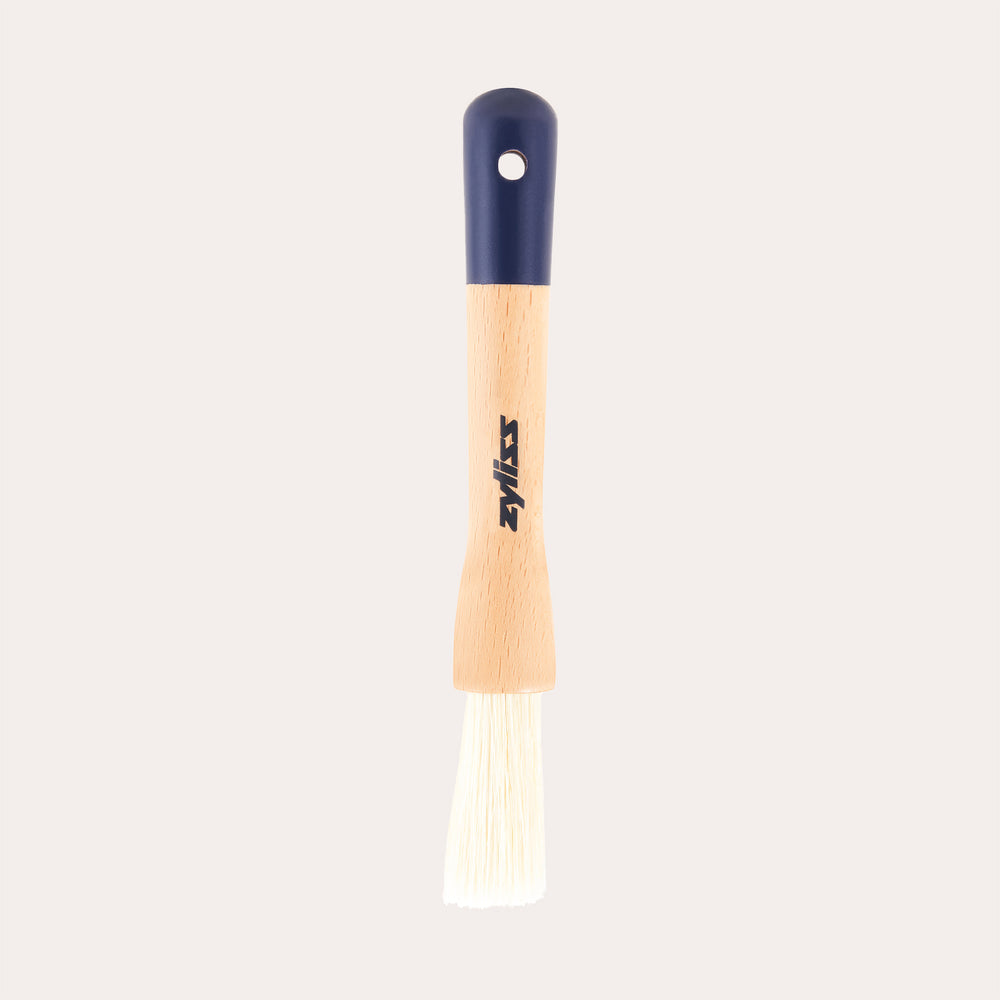 The Zyliss Beech Wood Pastry Brush features natural bristles, a beech wood handle with a printed logo, dark blue top, and hanging hole, shown on a plain white background.