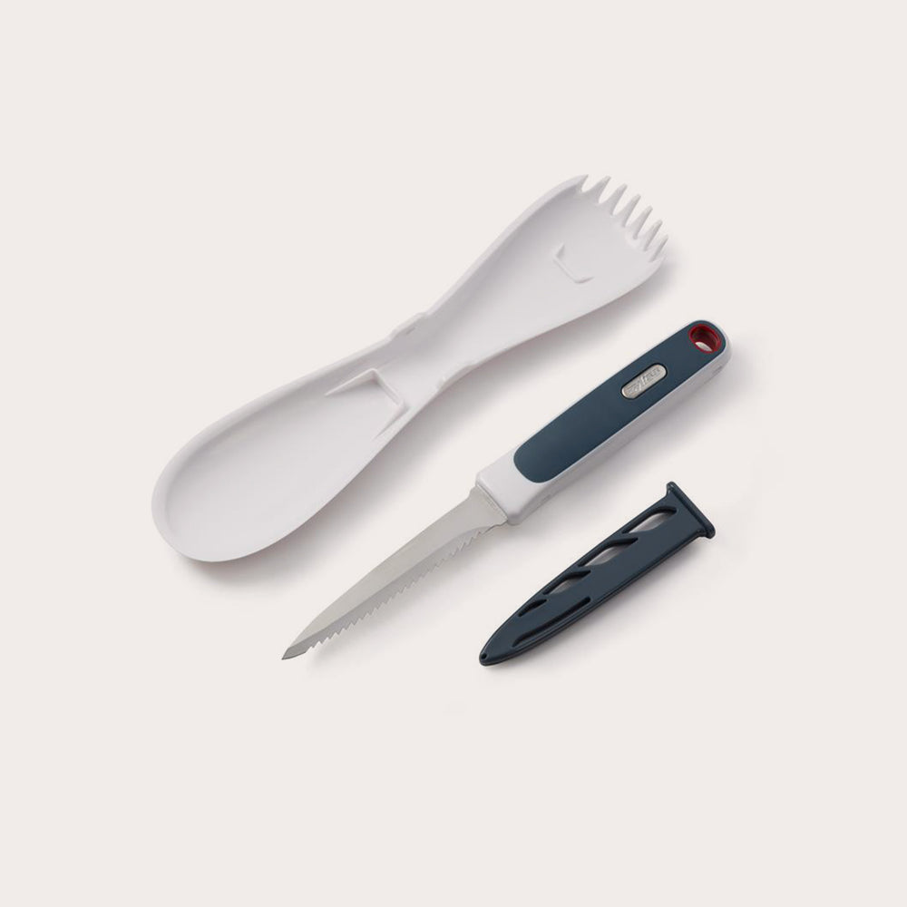 The Zyliss 3 In 1 Pumpkin & Squash Scoop & Knife set features a white plastic spork, spoon, serrated knife with black handle—ideal for pumpkin carving—and a black knife sheath, all arranged on a light background.