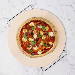A homemade pizza with tomato sauce, mozzarella, black olives, and basil sits on the Zyliss Ceramic Baking Stone atop marble, featuring a golden crust.