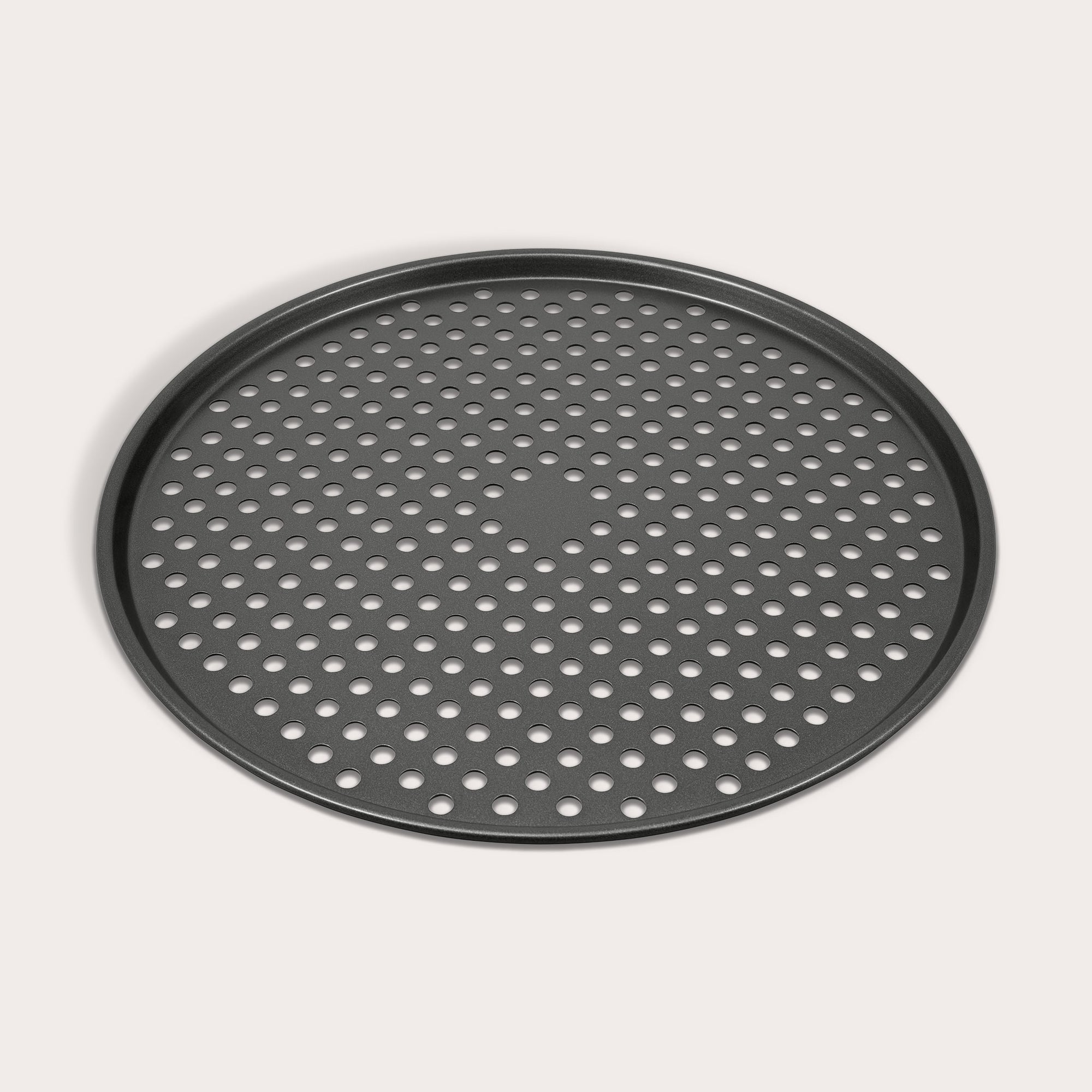 The Zyliss Non-Stick Pizza Tray is a round, black, carbon steel tray featuring numerous evenly spaced holes for crispy pizza bases. Shown on a white background.