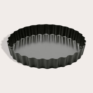 The Zyliss Non-Stick Tart Pan is round and black with fluted edges, a flat bottom, and a removable base—ideal for baking tarts or quiches. The empty pan is displayed on a light background.