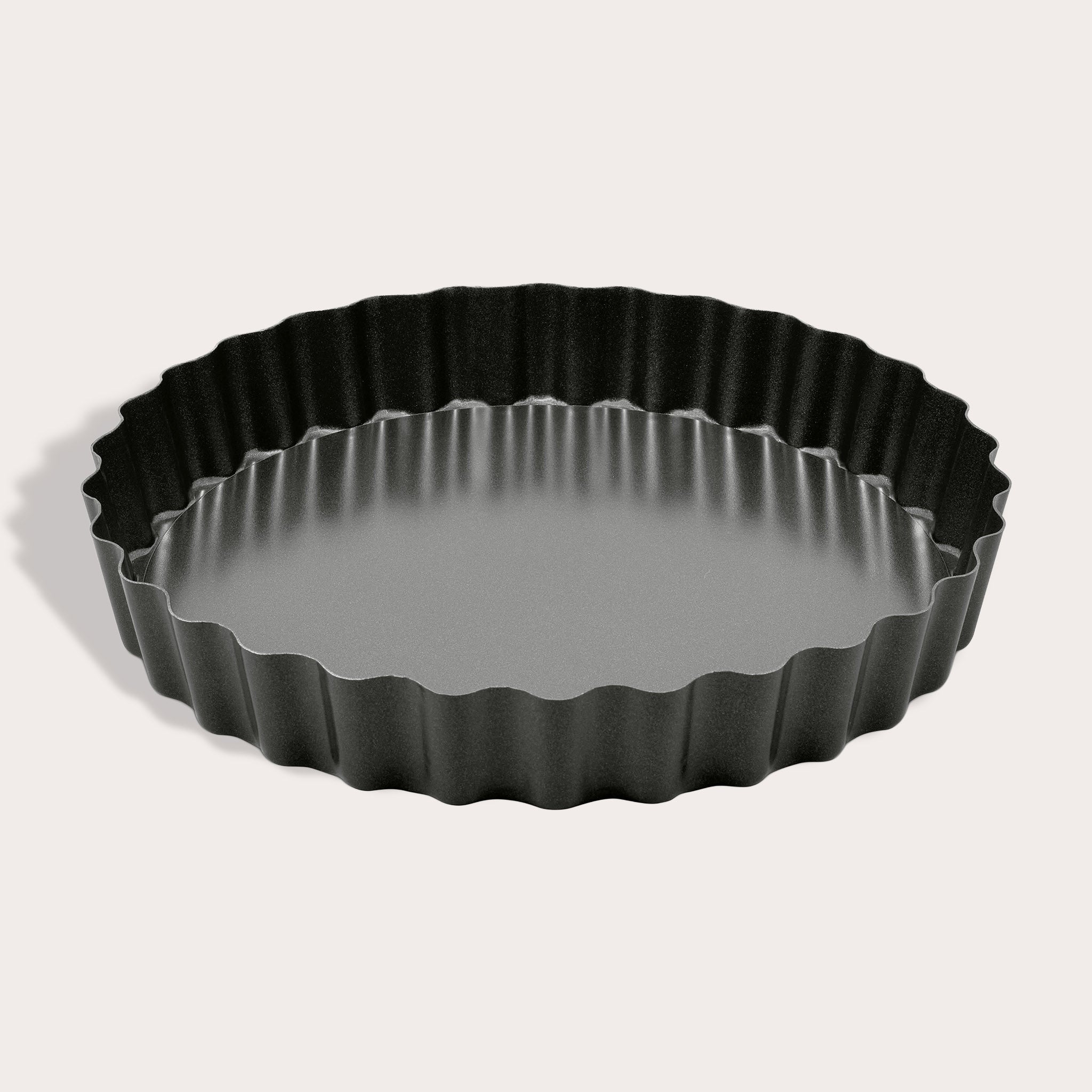 The Zyliss Non-Stick Tart Pan is round and black with fluted edges, a flat bottom, and a removable base—ideal for baking tarts or quiches. The empty pan is displayed on a light background.