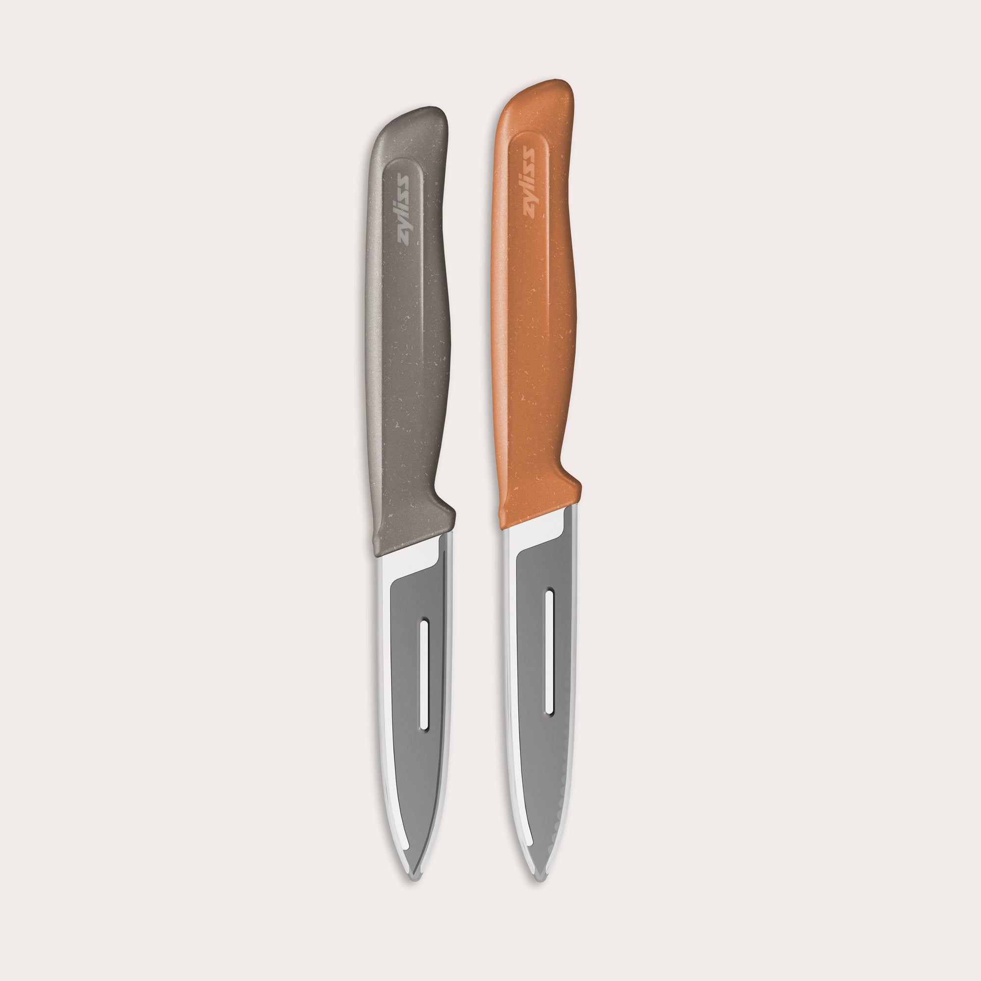 The Zyliss 2 Piece Knife Set features a serrated paring knife with a gray handle and a precision peeling knife with an orange handle, displayed side by side on a light background.