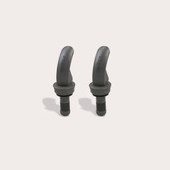 Two black, curved Zyliss Bottle Stopper 2 Piece Set items with a matte finish are displayed upright on a light beige background, featuring sleek designs that resemble wireless earbuds and small brand markings on their surfaces.