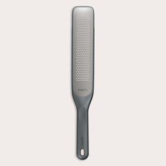 #belugagrey The Zyliss Rasp Grater is a long, rectangular foot file with a gray handle and textured metal surface for removing calluses and dead skin. The handle features a hanging hole for easy storage. 