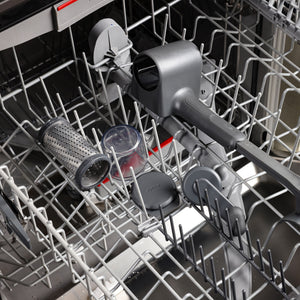 A Zyliss Professional Rotary Cheese Grater Set with detachable container and ergonomic crank, along with other gray and clear kitchen tools, sits on the top rack of an open dishwasher, ready for cleaning.