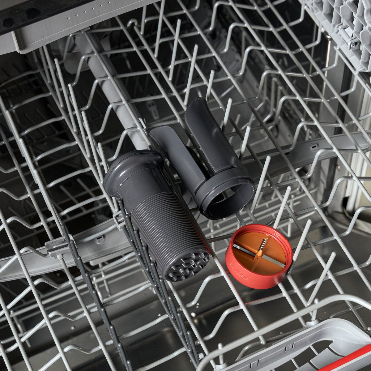 A Zyliss Vegetable Spiralizer with Reversible Blade and Food Pusher sitting in the rack of an empty dishwasher.