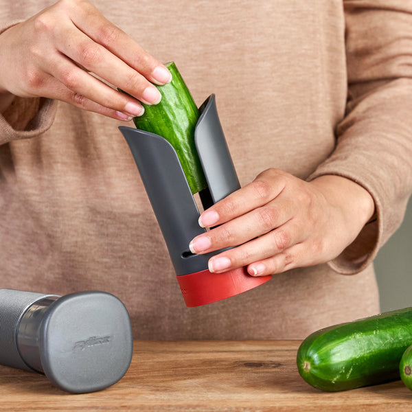 Hands placing a cucumber into a Zyliss Vegetable Spiralizer with Reversible Blade and Food Pusher.