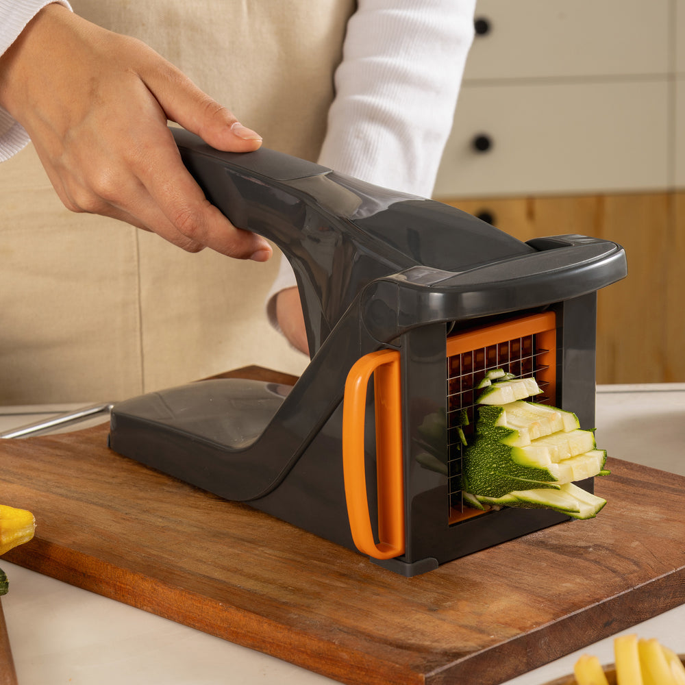 The Zyliss Potato & Vegetable Chipper is a black handheld cutter with two interchangeable stainless steel blades (orange and red) for uniform slicing. Dishwasher safe for easy cleaning.