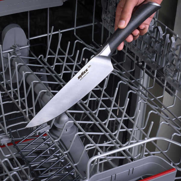 A hand holding a Zyliss Comfort Pro Prep Trio Knife over an open dishwasher rack, preparing to place the knife inside the dishwasher.