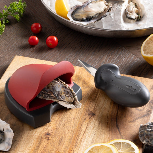 zyliss oyster shucking set holding an oyster on a wooden board, with the knife beside it.