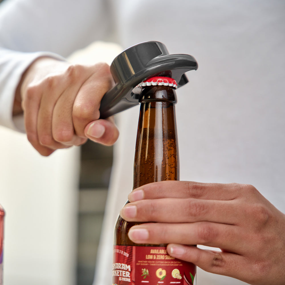 The Zyliss 5 In 1 Opener is a compact, metallic bottle opener with an ergonomic grip, wide handle, and circular opening for removing caps, shown on a plain light background.