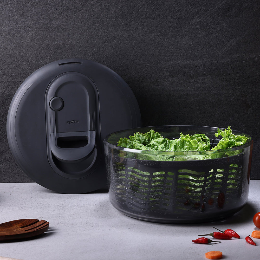 The Zyliss Easy Spin Salad Spinner features a clear plastic bowl, dark gray lid and handle, AquaVent technology, and a visible inner basket—making it a smart pick for any eco-friendly kitchen.