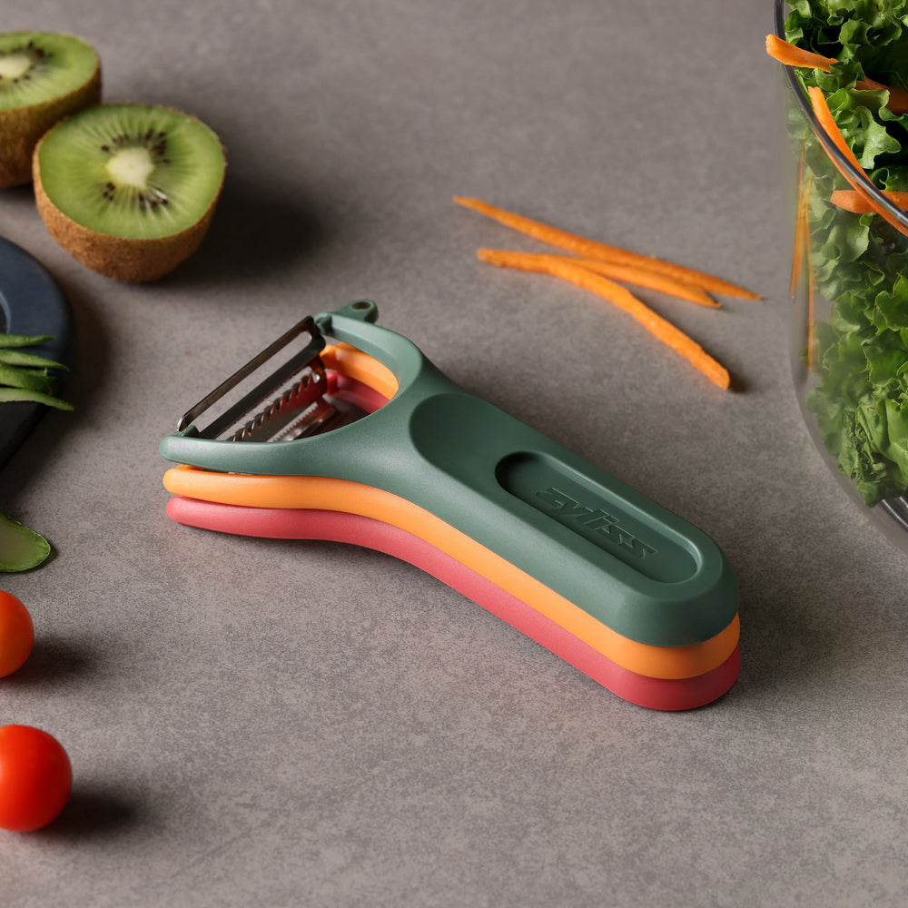 The Zyliss 3 Piece Y Peeler Set features ergonomic handles and Swiss-made stainless steel blades in green, orange, and red, stacked vertically against a plain light background.
