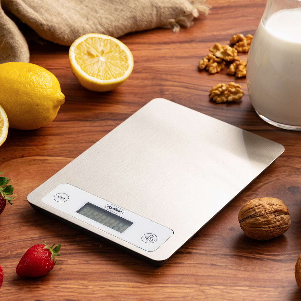 The Zyliss Digital Food Scale features a stainless steel surface, precision weighing, and displays 125 grams. It has unit and tare buttons next to the display for easy use.