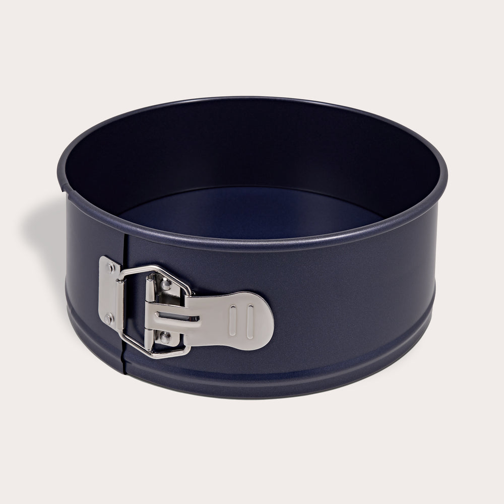 The Zyliss Durable Non-Stick Springform Cake Pan features a round black design with a silver latch, ideal for baking delicate cheesecakes, and is shown against a plain light background.