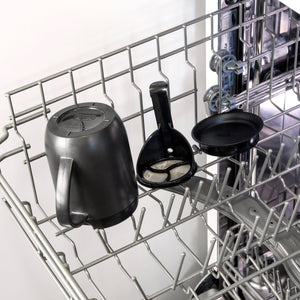 A Zyliss Hot Mug Cafetière Mug, along with its black coffee filter holder and filter lid, sits on the open dishwasher's top rack, ready for cleaning.