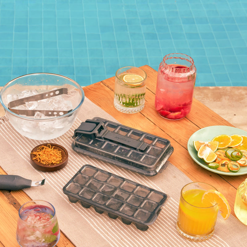 Two Zyliss Press & Pull ice cube trays beside fruit and drinks at a poolside table