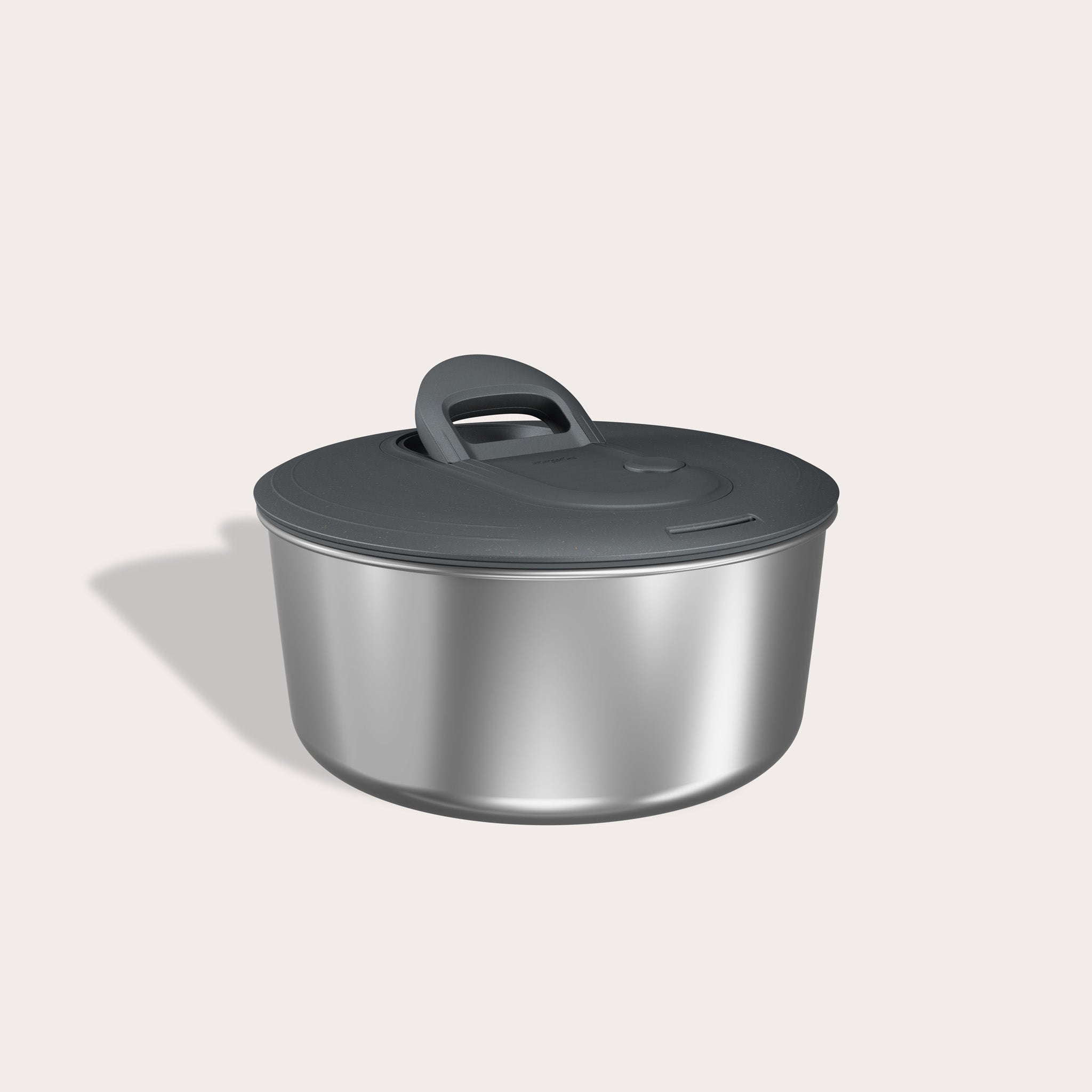 The Zyliss Easy Spin Salad Spinner Stainless Steel, with a matching dark gray lid and large handle, sits on a light background casting a soft shadow to the left.