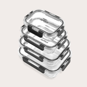 A stack of four clear rectangular glass food containers with black locking lids, arranged neatly on a light background.