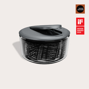 The Zyliss Swift Dry Salad Spinner, featuring a modern black and transparent design with a one-handed pump and lid, is shown against a light background. Good Design and iF Design Award 2026 logos appear on the right.