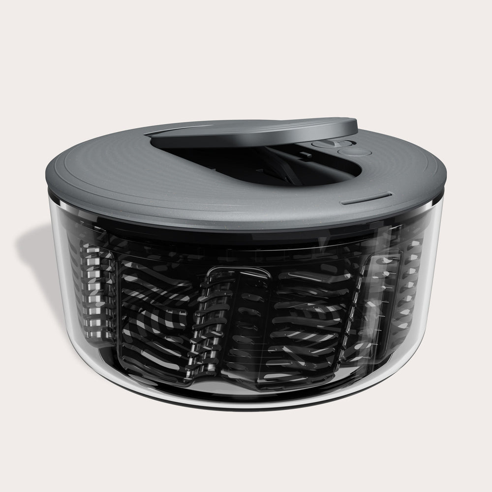 The Zyliss Swift Dry Salad Spinner features a clear bowl, gray lid, and black spiral mechanism, offering easy one-handed operation as a modern kitchen gadget for washing and drying salad.