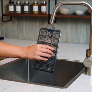 Filling a zyliss Classic Ice Cube Tray with water from a faucet.