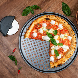 A homemade Margherita pizza with mozzarella, tomato, and basil sits on the Zyliss Pizza Tray & Cutter Bundle. Pizza slices are missing, and nearby rest fresh basil leaves and red chili peppers.