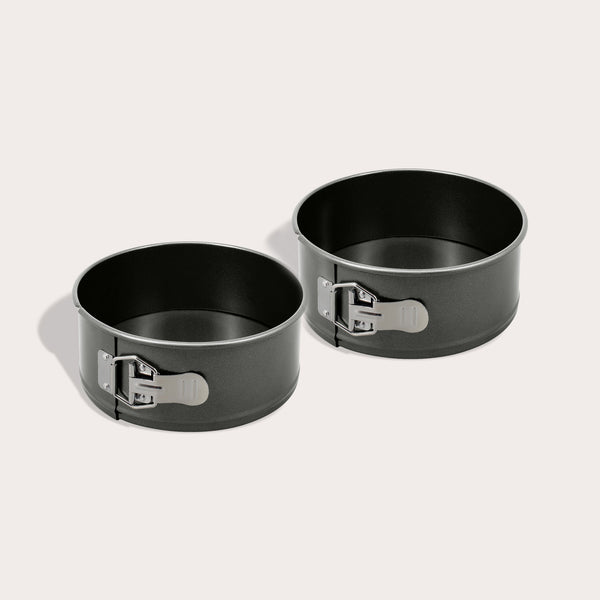 The Zyliss Springform Cake Pan 2 Piece Set, each 20cm/9", features round black non-stick pans with metal latches, shown side by side on a light surface with soft shadows.