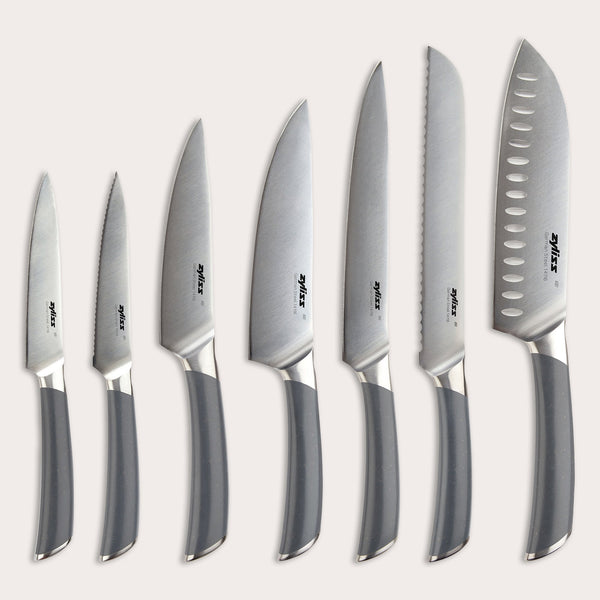 The Zyliss Comfort Pro 7-Piece Complete Knife Collection features seven kitchen knives with silver blades and gray handles, each expertly arranged for the perfect balance of versatility and precision—making it an ideal set to handle all your kitchen tasks, from everyday prep work to precise slicing with a chef’s knife.