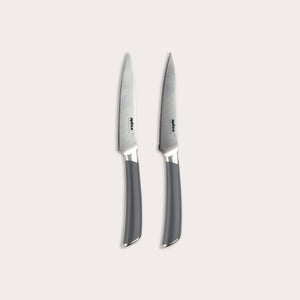 The Zyliss Comfort Pro Paring Knife Set features two stainless steel paring knives with gray handles, displayed side by side on a light background. The set includes one smooth-edged knife and one serrated paring knife, providing versatility for all your kitchen prep needs.