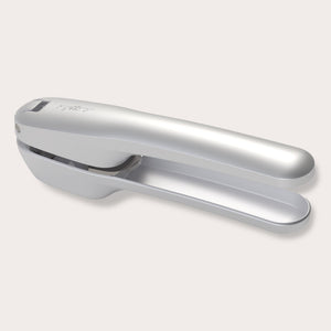 The Zyliss Susi 4 Garlic Press, featuring ergonomic handles and a sleek silver design, is shown closed on a plain light background, offering easy cleanup.