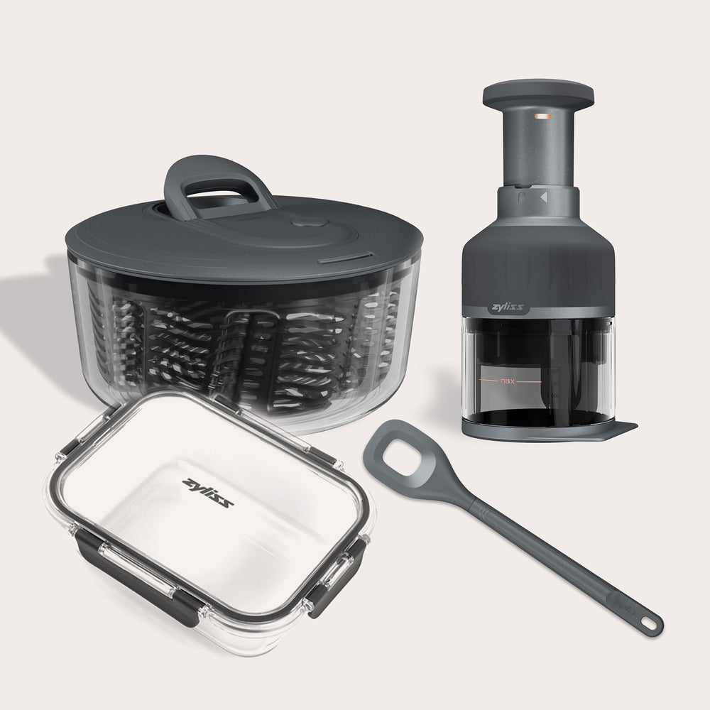 The Zyliss Healthy Meal Prep Bundle includes a black salad spinner, clear food storage container with black lid, manual veggie chopper, and black spatula—ideal essentials for healthy meal prep.
